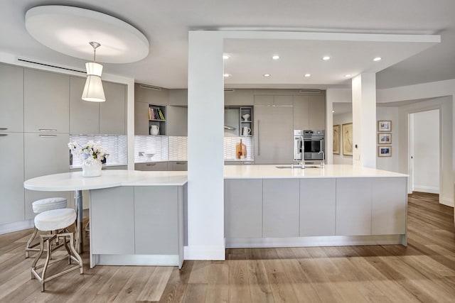 kitchen featuring light countertops, light wood-style flooring, modern cabinets, tasteful backsplash, and gray cabinetry