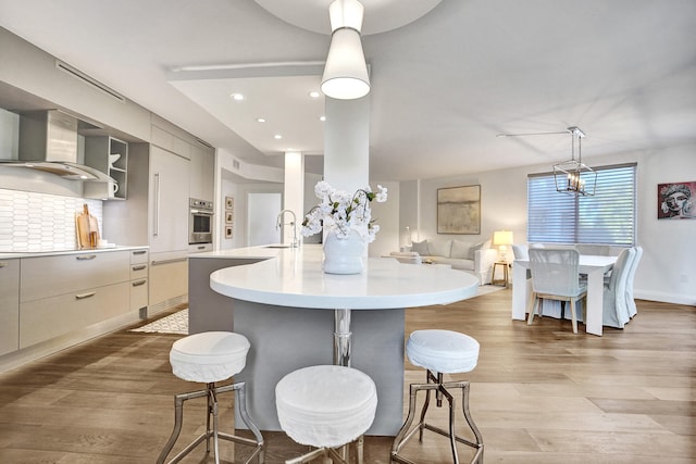 kitchen with light countertops, a sink, a kitchen bar, light wood-style floors, and oven