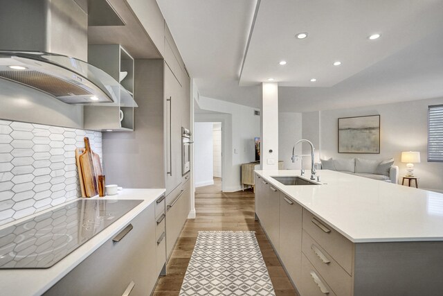 kitchen with black electric cooktop, island exhaust hood, modern cabinets, a sink, and dark wood-style floors