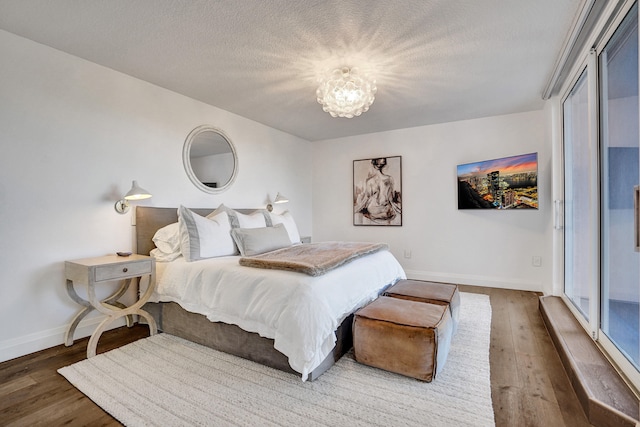 bedroom with baseboards, an inviting chandelier, wood finished floors, and a textured ceiling