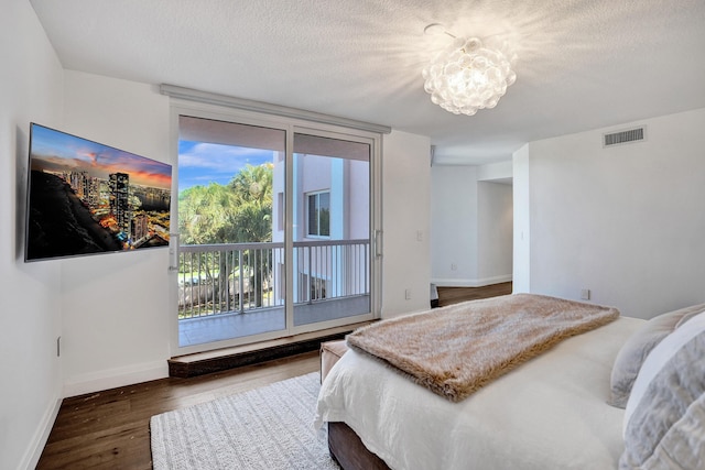 bedroom with visible vents, a textured ceiling, baseboards, and wood finished floors