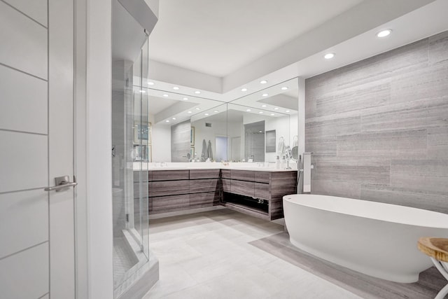 full bathroom with tile walls, a soaking tub, recessed lighting, vanity, and a stall shower