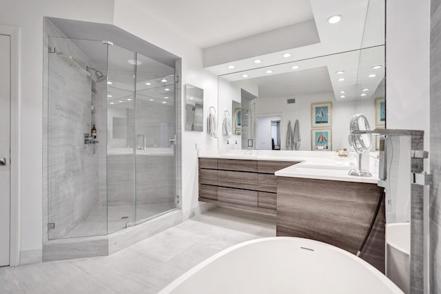 bathroom featuring double vanity, a stall shower, and a freestanding bath