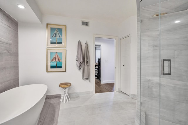 bathroom featuring a freestanding tub, baseboards, visible vents, and a stall shower