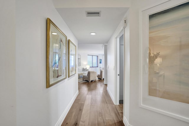 hallway featuring hardwood / wood-style floors, baseboards, and visible vents