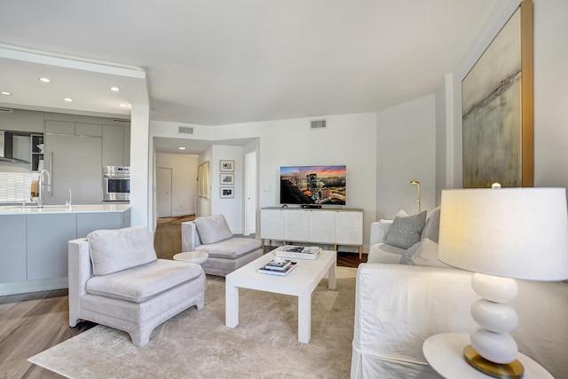 living area with light wood-type flooring, recessed lighting, and visible vents