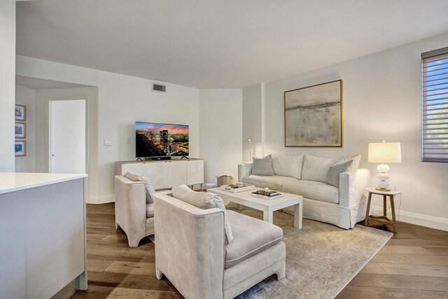 living room featuring baseboards, visible vents, and hardwood / wood-style flooring