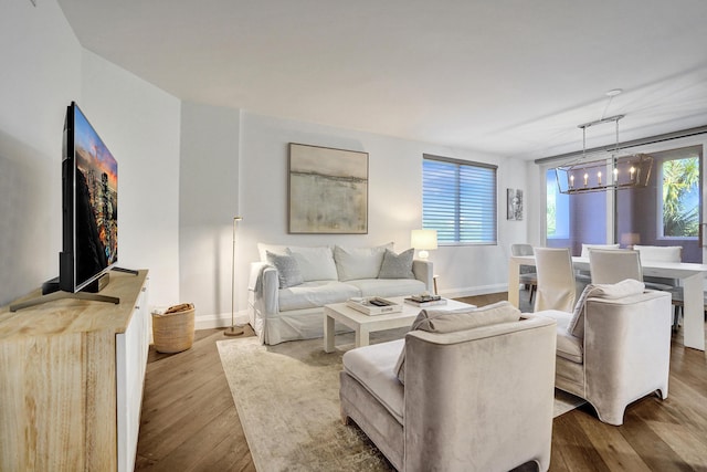 living room featuring baseboards, hardwood / wood-style flooring, and a chandelier