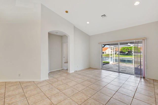 unfurnished room featuring light tile patterned floors, baseboards, visible vents, arched walkways, and recessed lighting