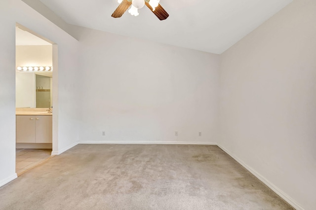 spare room featuring light carpet, baseboards, ceiling fan, and light tile patterned floors