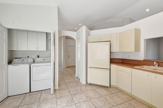 kitchen with independent washer and dryer, cream cabinetry, a sink, light tile patterned flooring, and freestanding refrigerator