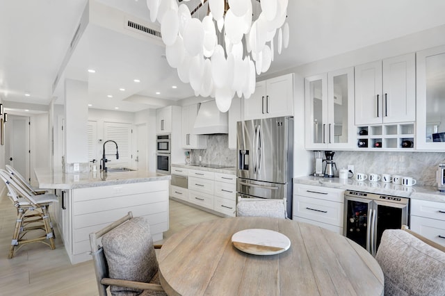 1149 Hillsboro Mile Unit 112N, Hillsboro Beach, FL 33062 - kitchen featuring custom range hood, beverage cooler, visible vents, white cabinets, and appliances with stainless steel finishes