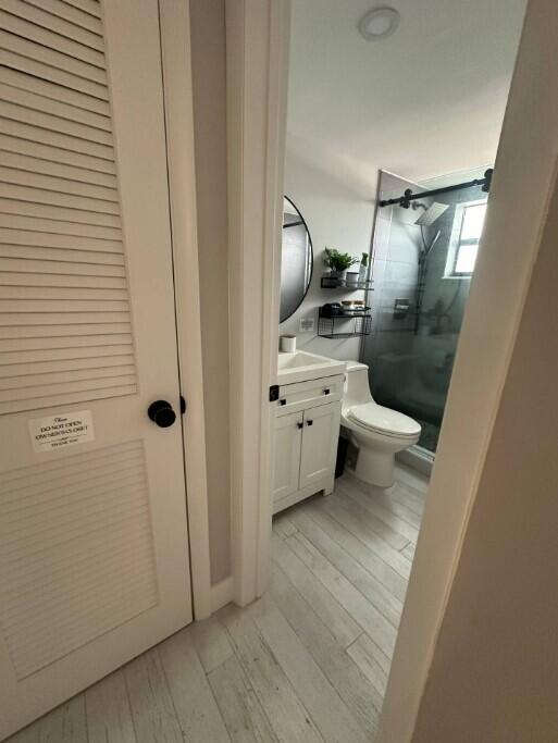 664 SE 20th Ave Unit 1, Deerfield Beach, FL 33441 - bathroom with vanity, wood finished floors, toilet, and a shower stall