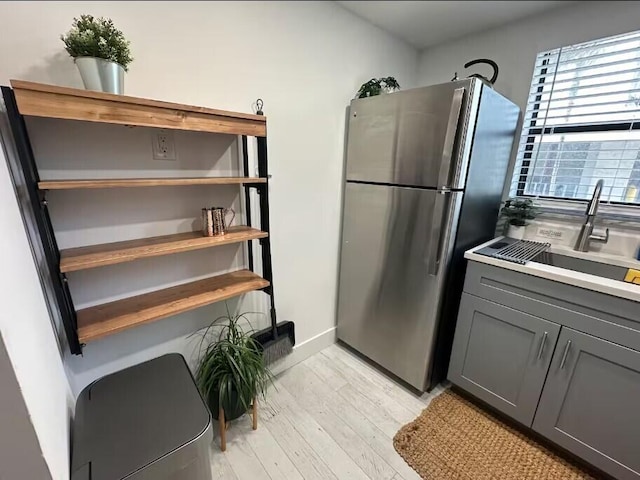 664 SE 20th Ave Unit 1, Deerfield Beach, FL 33441 - kitchen with light wood-type flooring, gray cabinetry, light countertops, a sink, and freestanding refrigerator