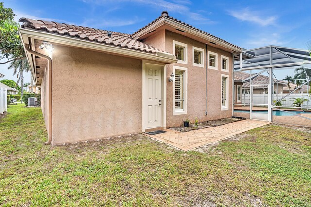 11604 Kensington Ct, Boca Raton, FL 33428 - rear view of property featuring glass enclosure, a fenced in pool, a yard, a patio, and stucco siding
