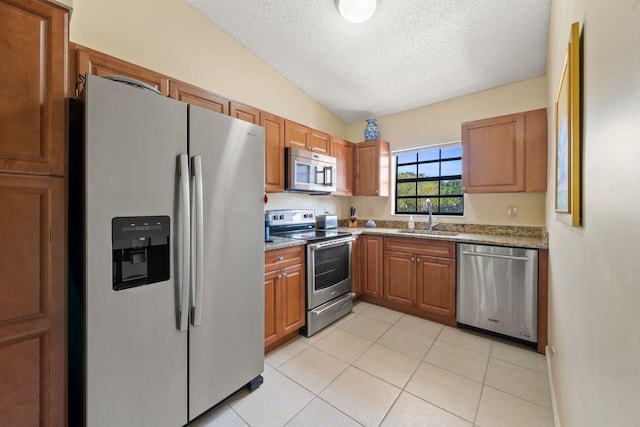 301 Norwood Ter Unit N230, Boca Raton, FL 33431 - kitchen featuring lofted ceiling, brown cabinetry, a sink, and stainless steel appliances