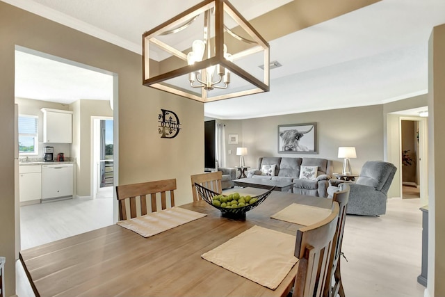 dining area featuring crown molding, visible vents, light wood-type flooring, and a notable chandelier