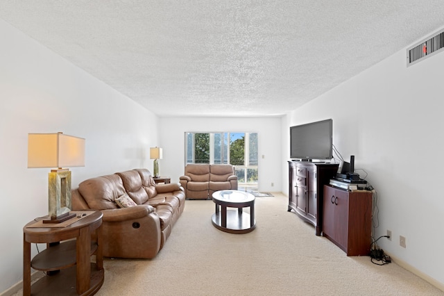 living room with baseboards, a textured ceiling, visible vents, and light colored carpet