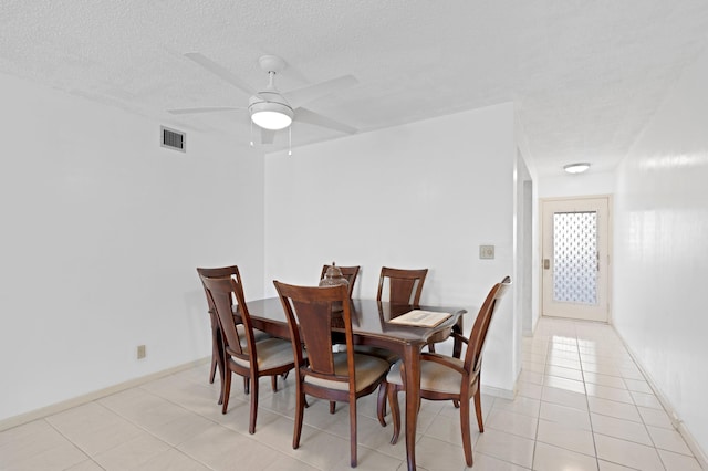 dining room with a textured ceiling, visible vents, baseboards, a ceiling fan, and light tile patterned floors