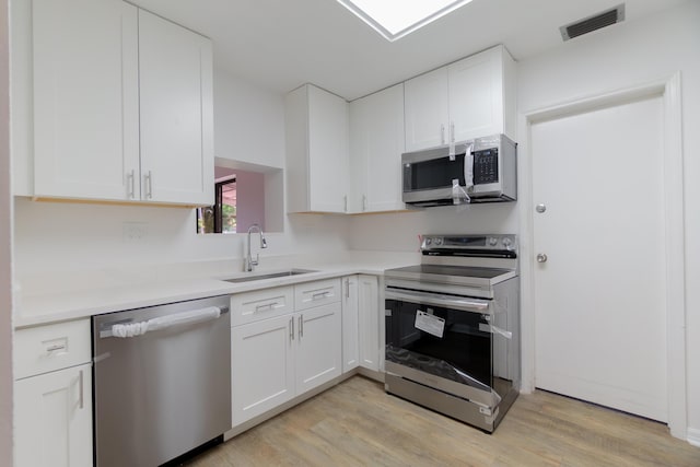4375 Forest Ln, Palm Springs, FL 33406 - kitchen with stainless steel appliances, a sink, white cabinetry, and light wood-type flooring