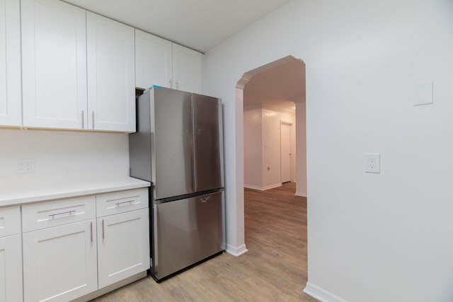 4375 Forest Ln, Palm Springs, FL 33406 - kitchen with freestanding refrigerator, arched walkways, light wood-style floors, white cabinets, and light countertops