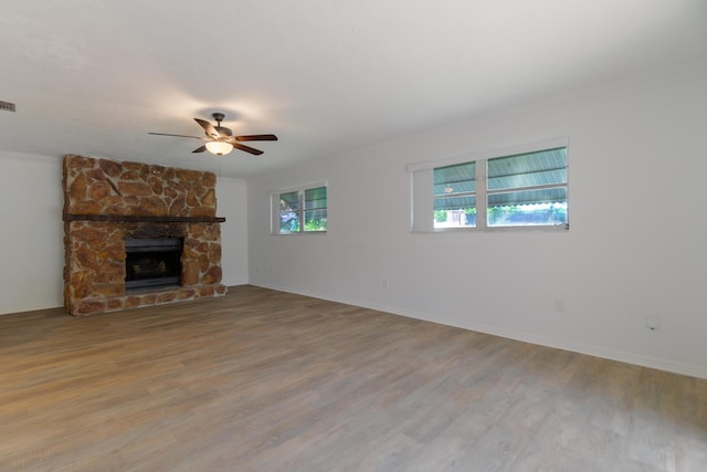 4375 Forest Ln, Palm Springs, FL 33406 - unfurnished living room featuring ceiling fan, wood finished floors, ornamental molding, baseboards, and a stone fireplace