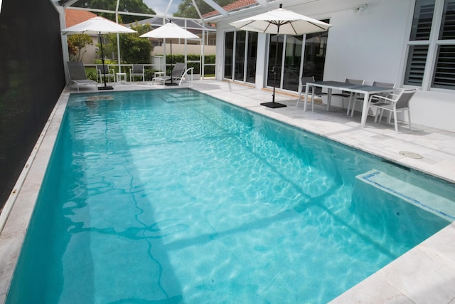 view of pool featuring glass enclosure, a fenced in pool, and a patio