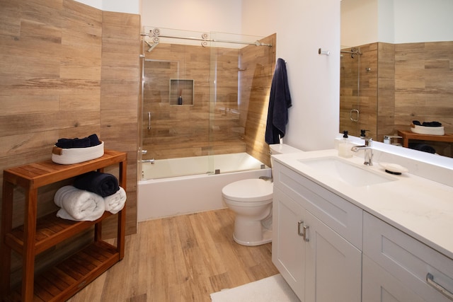 full bathroom featuring toilet, vanity, enclosed tub / shower combo, and wood finished floors