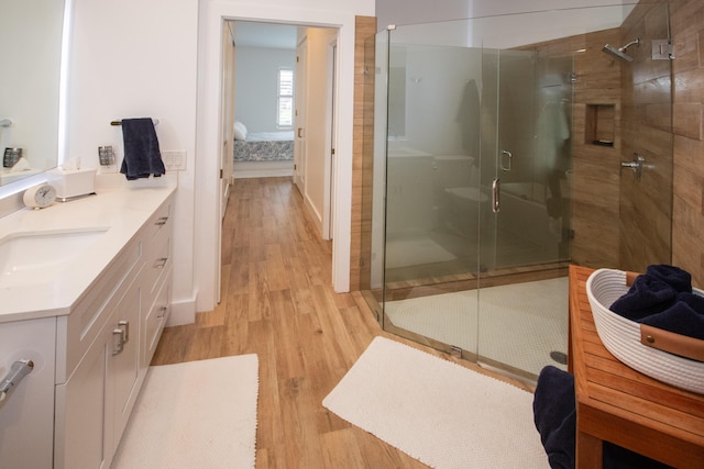full bath with connected bathroom, wood finished floors, vanity, and a shower stall