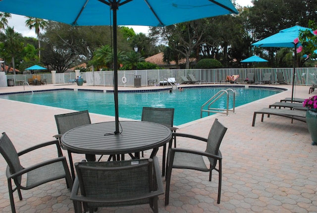 community pool with fence and a patio