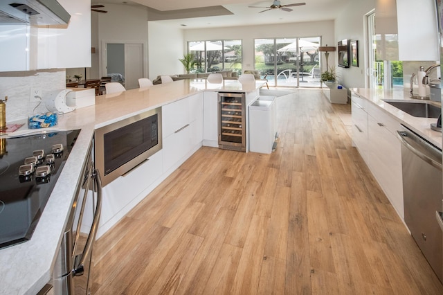 kitchen with white cabinetry, wine cooler, built in microwave, a ceiling fan, and modern cabinets