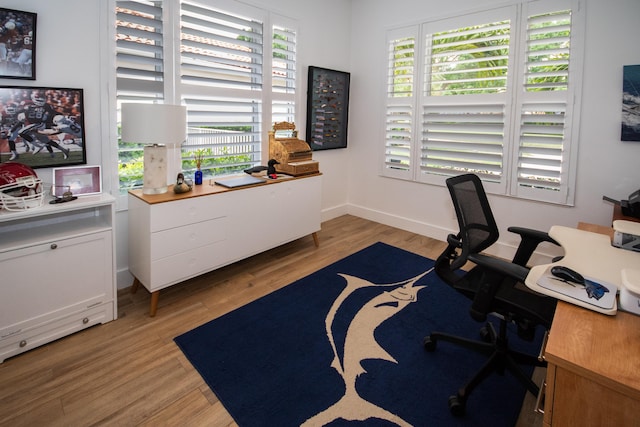 home office featuring light wood-style flooring, baseboards, and a healthy amount of sunlight
