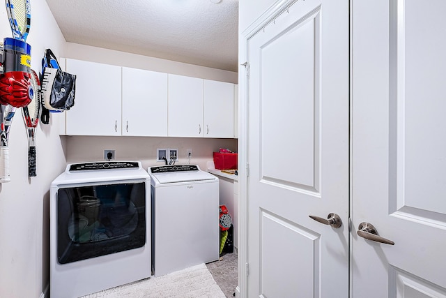 washroom with a textured ceiling, cabinet space, and washing machine and clothes dryer