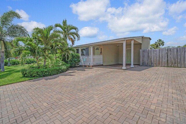 view of property hidden behind natural elements featuring a front yard, decorative driveway, and fence