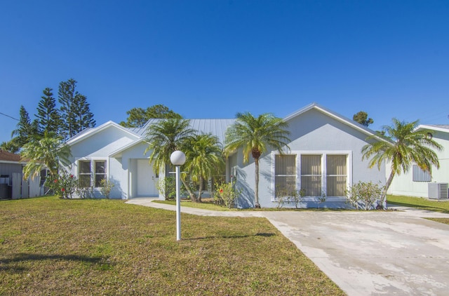 ranch-style house with a standing seam roof, stucco siding, a front lawn, metal roof, and central AC