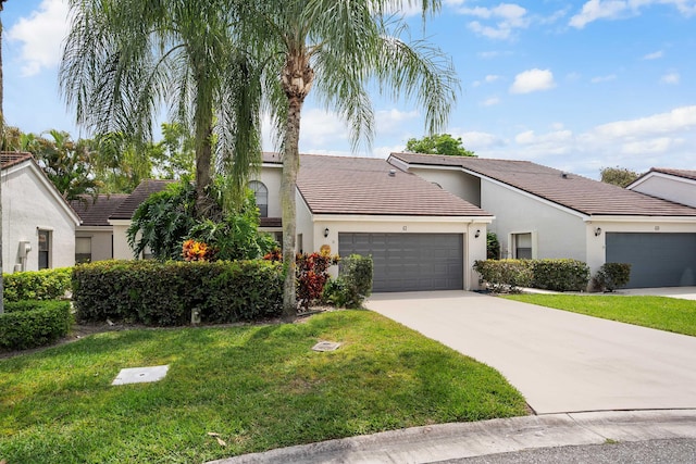 view of front of property with stucco siding, a front yard, a tile roof, a garage, and concrete driveway