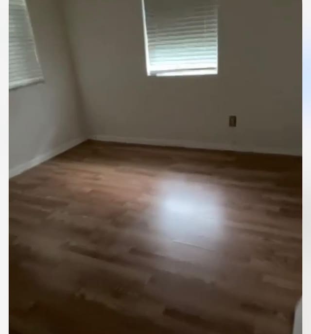 spare room with baseboards and wood finished floors