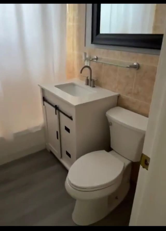 bathroom featuring tile walls, toilet, and vanity