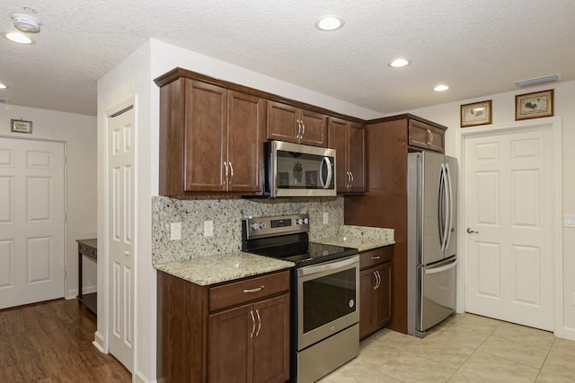 6763 Mar Pacifico, Fort Pierce, FL 34950 - kitchen featuring stainless steel appliances, decorative backsplash, visible vents, light stone countertops, and dark brown cabinets