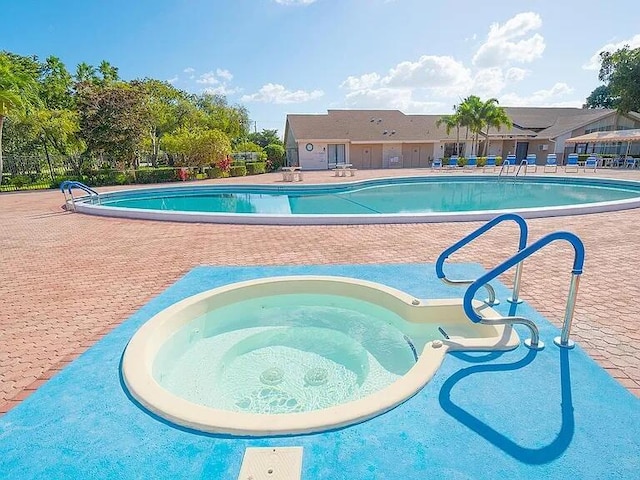 pool with a community hot tub, a patio area, and fence