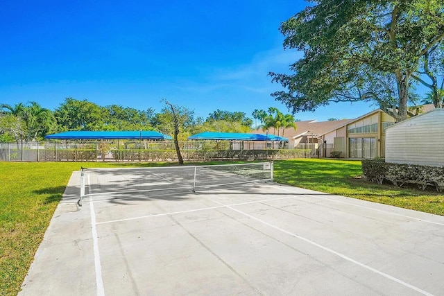 view of property's community with a tennis court, fence, and a lawn