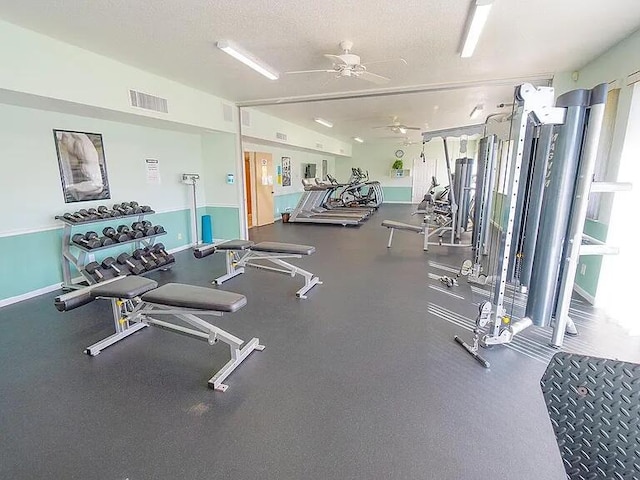workout area featuring a textured ceiling, baseboards, a ceiling fan, and visible vents