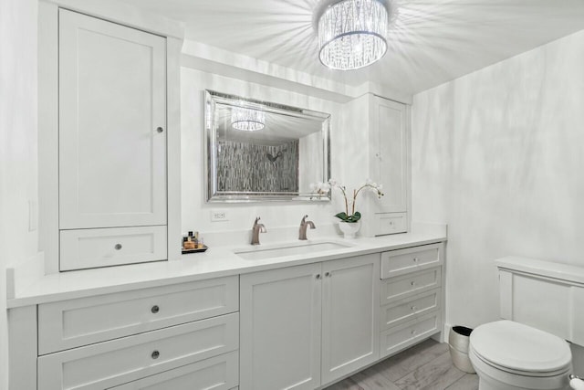 bathroom featuring toilet, an inviting chandelier, wood finished floors, and vanity