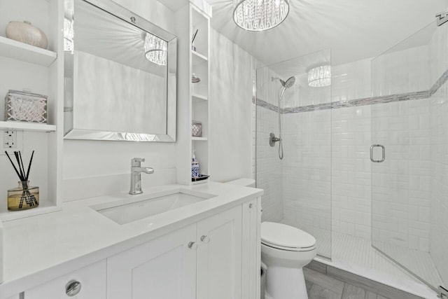 full bath featuring an inviting chandelier, vanity, a shower stall, and toilet