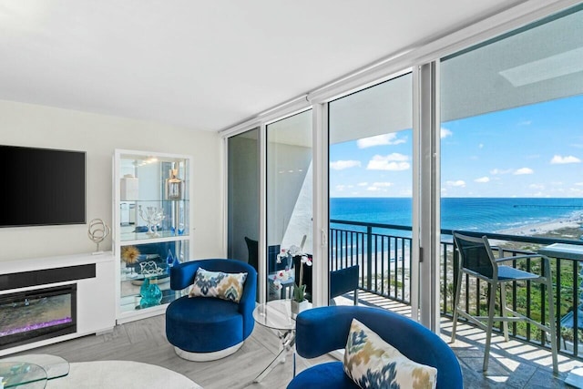 interior space with a water view, a wall of windows, and a glass covered fireplace