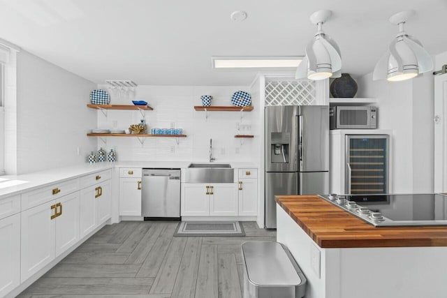kitchen featuring open shelves, a sink, beverage cooler, wooden counters, and stainless steel appliances