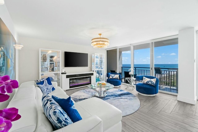 living area featuring expansive windows, a glass covered fireplace, and a chandelier