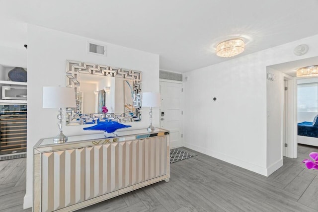 interior space featuring beverage cooler, baseboards, wood finished floors, and visible vents