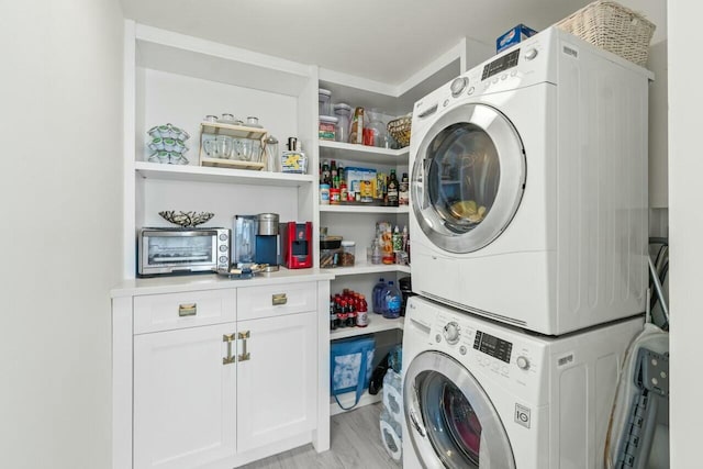 washroom with cabinet space, stacked washer and dryer, and light wood-style floors