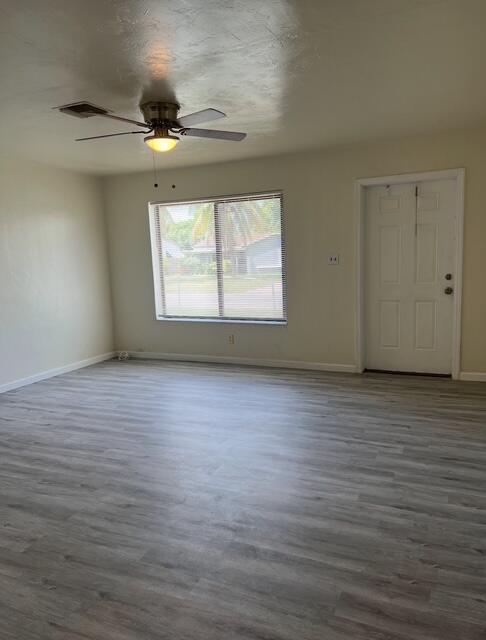 spare room featuring baseboards, wood finished floors, and a ceiling fan